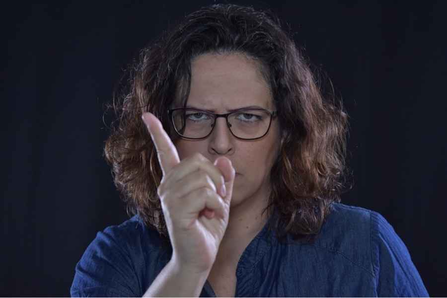 man with glasses frowning and holding up a finger