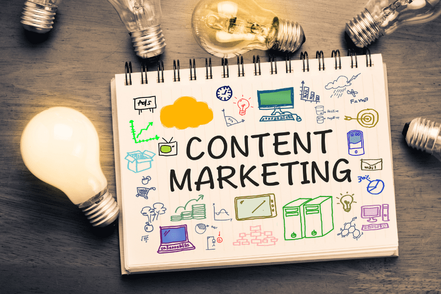 Content-marketing-definition-notebook-and-lightbulbs-900x600 The words "Content Marketing" written in a notebook.